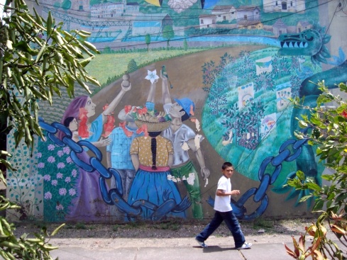 A schoolboy walks past a huge mural at the side of an apartment building.