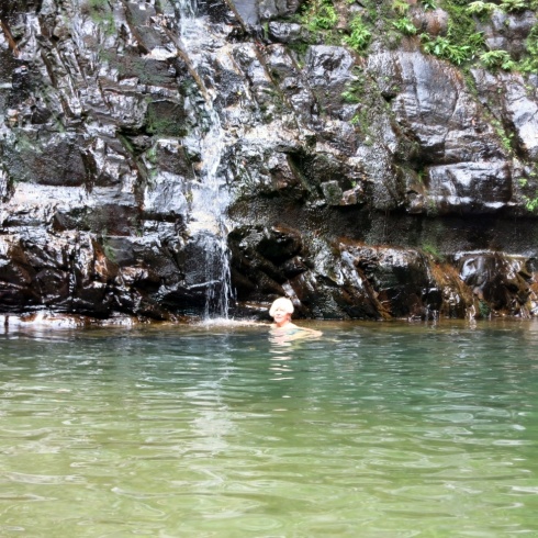 Marissa swimming near the trickle of a waterfall.