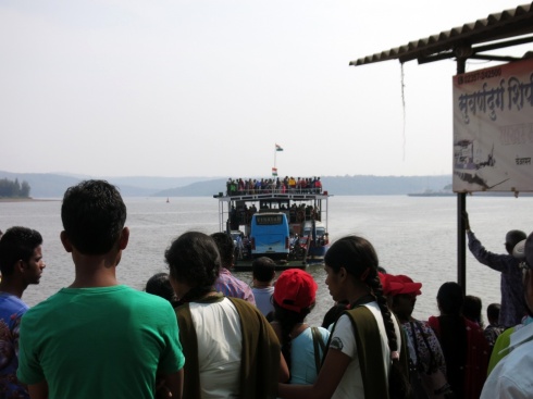 A packed ferry approaches from the other side of the river-mouth.